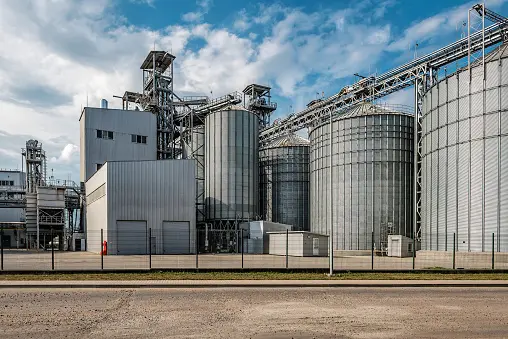 imagen de campo de girasoles con fabrica de aceites industrial